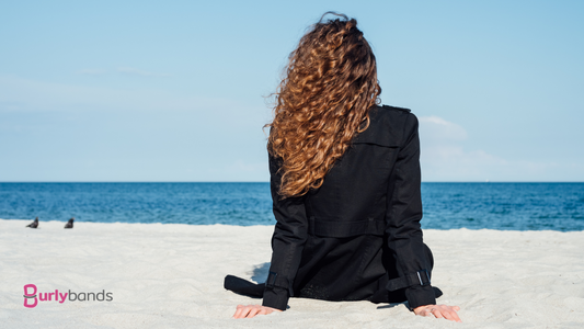 Girl sitting on the beach facing the sea