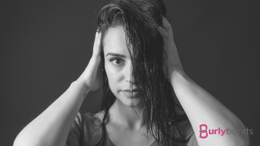 A black and white photo of a lady with her hands in her wet looking hair