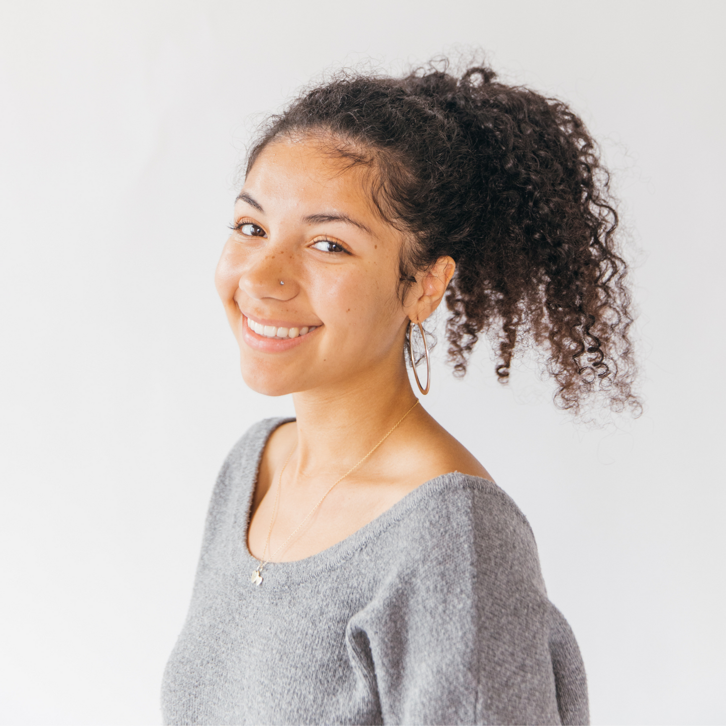 girl with thick curly hair and gray sweater, wearing a burlyband hair ties for thick hair