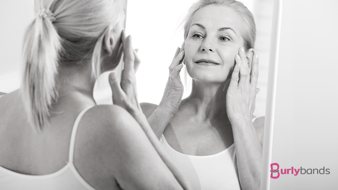 older woman touching face while looking in mirror